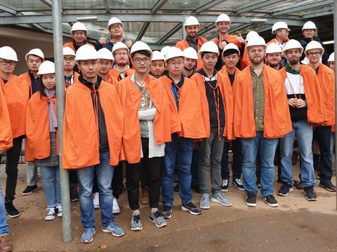 Gruppenfoto von Mitarbeiter, alle haben orangene Regenjacken und Schutzhelme an