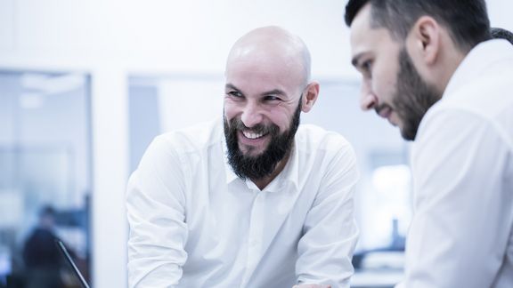 zwei junge männliche Mitarbeiter stehen da und lachen