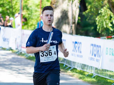 junger männlicher Mitarbeiter rennt bei einem Staffellauf zur Kamera