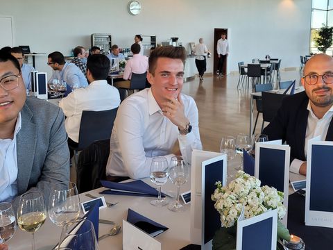 Mitarbeiter sitzen an einem Tisch mit blauer Tischdekoration und weißen Blumen